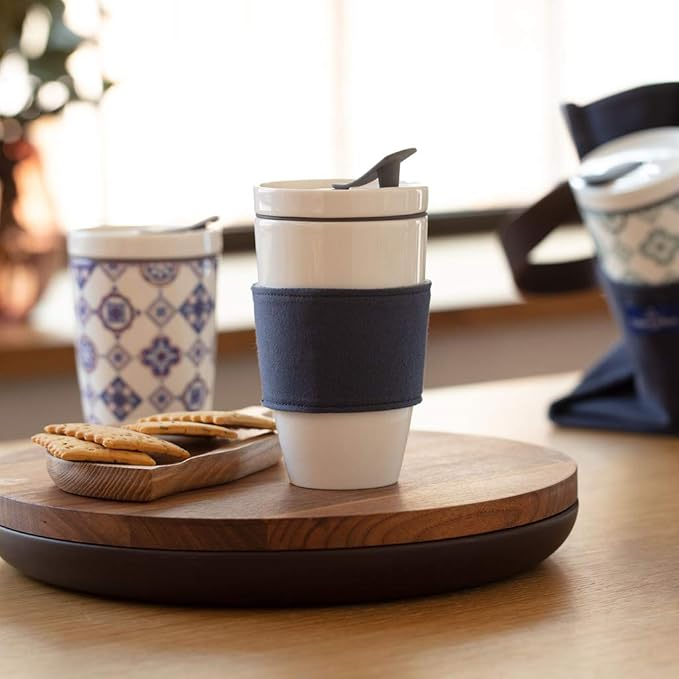 Mug de transport Villeroy & Boch en porcelaine blanche avec couvercle en silicone, posé sur une table